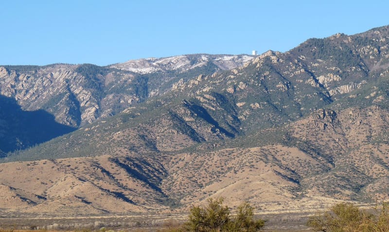 Bangunan pelindung Large Binocular Telescope di puncak berhutan Pegunungan Pinaleno, Arizona, terlihat dari kejauhan