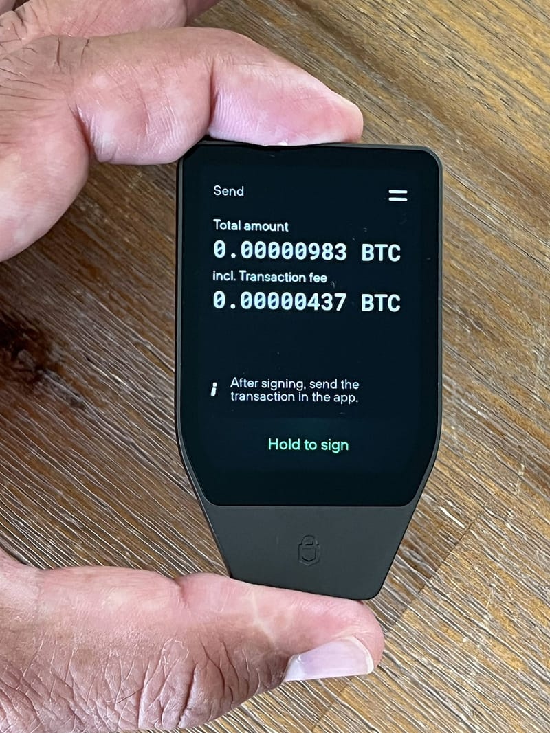 A hardware crypto wallet displaying a Bitcoin transaction on its screen for manual confirmation