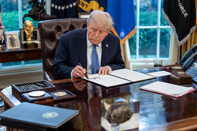 President Donald Trump signing executive orders at the Resolute Desk in the Oval Office (file photo, April 2025)