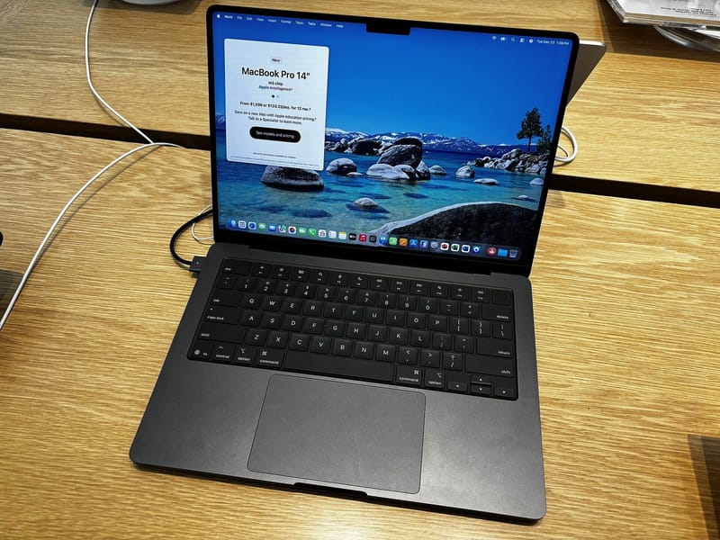 Current 14-inch Apple MacBook Pro with M5 chip in Space Black, seen from above with macOS on screen