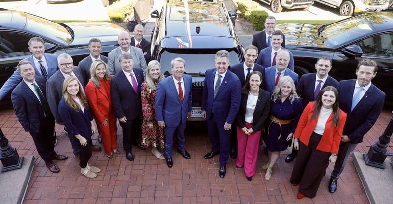 Georgia Gov. Brian Kemp with Audi executives and state officials beside a black Audi SUV after the Audi Georgia plant announcement