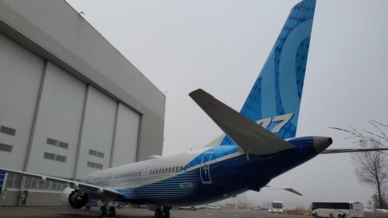 Vista traseira do primeiro avião de testes Boeing 737-10, matrícula N27751, com pintura azul da Boeing, estacionado ao lado de um hangar em um dia nublado